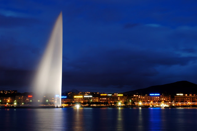 A picture of Jet d'Eau (Geneva Water Fountain). The water is spraying up with the night sky behind it